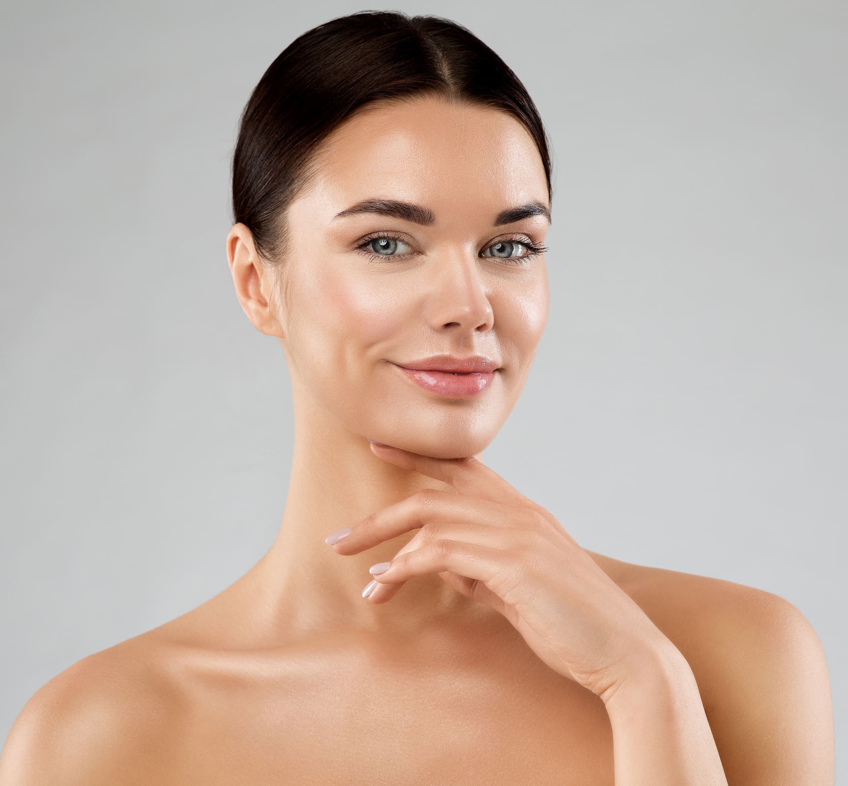 Beauty Model with Smooth Skin touching Chin. Happy Young Woman with Perfect Face Make up over White. Women Facial Spa Cosmetics and Anti Age Cosmetology. Female Plastic Surgery Neck Lift in Jacksonville, FL